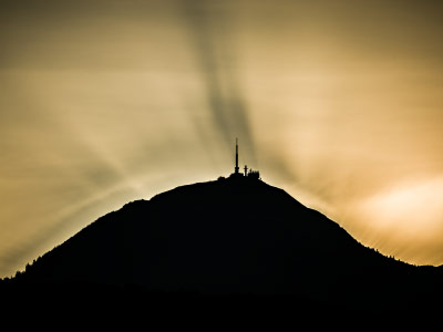 Les antennes du Puy-de-Dôme en ombre chinoise sur des nuages au coucher du soleil