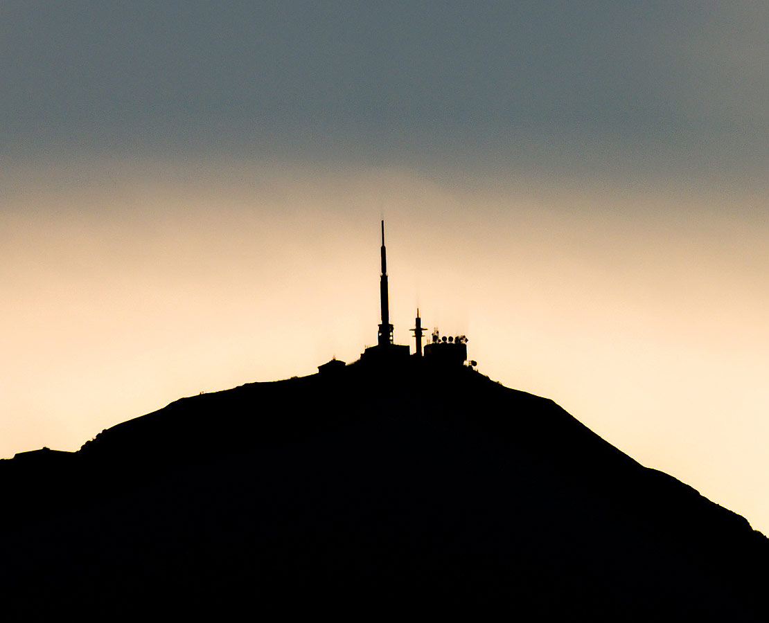 Le sommet du Puy-de-Dôme en ombre chinoise se projète sur un nuage au coucher du soleil